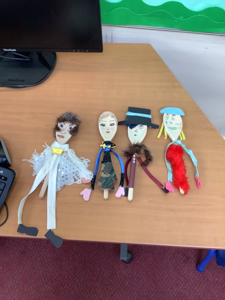 wooden spoons that look like elvis, a noble lady, someone with a top hat with a blue ribbon through it and a scarf and a lady with a red dress made of feathers